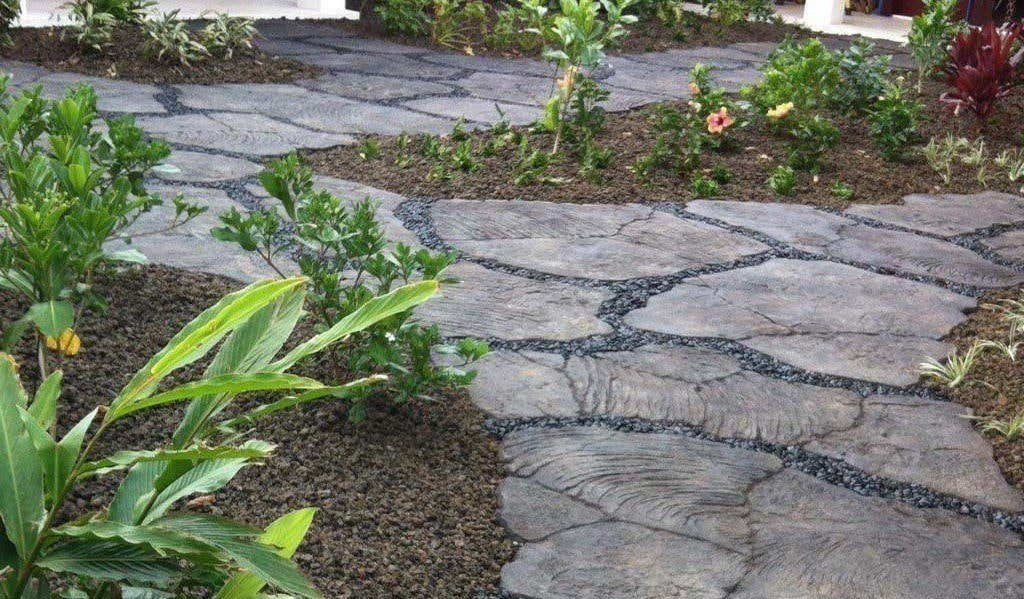 Kona flowerbed on Hawaii island. Flower bed has a flagstone walkway going around local flowers and shrubs.