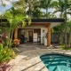 Canoe plants and vibrant tropical foliage surround a luxury swimming pool and open-air patio pavilion for Big Island landscaping.