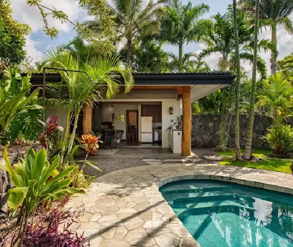 kona-lava-landscape-garden-transformation Backyard pool and patio wrapped in native tropical plants and stone walls, displaying a complete Kona lava landscape transformation.