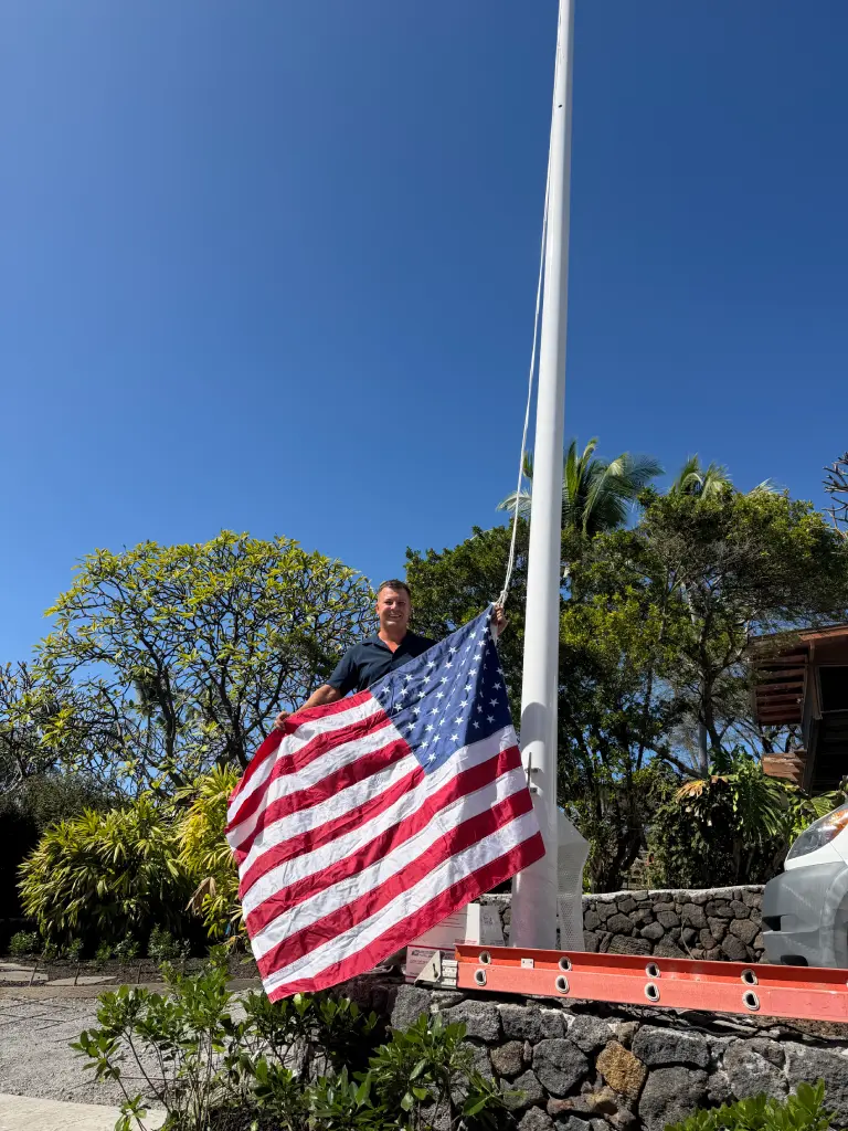 Aina-Landscaping company founder and owner, Kirill (Kerry) Vekhov holds up an American flag during a landscape installation project on the Big Island of Hawaii.