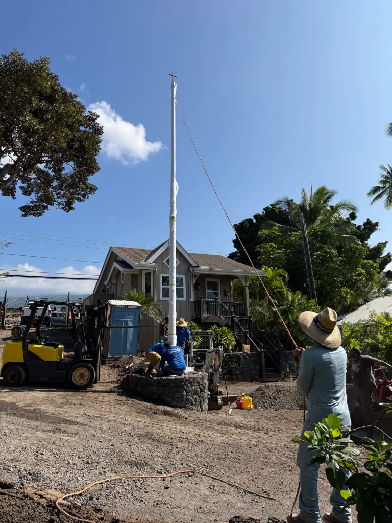 Kailua-Kona landscaping company team installs a flag pole on top of a lava rock retaining wall.