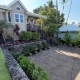 Completed estate landscape renovation in Kailua-Kona with restored lava rock walls, new plantings, and stamped concrete driveway at the ohana house.