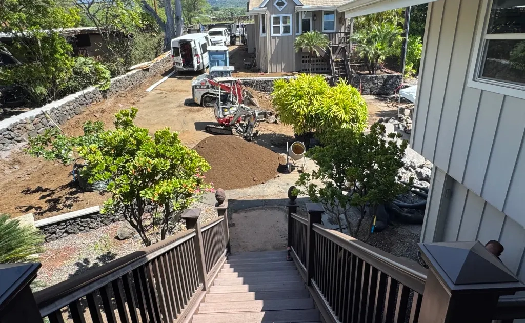 topsoil-and-hardscaping-kona Before photo of a Kailua-Kona estate during full landscape renovation, with a mini excavator and topsoil piles between the main house and ohana house.
